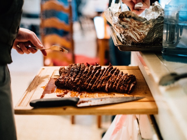 A guy is cutting his brisket